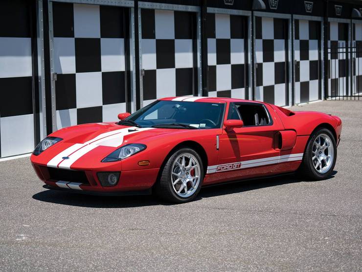 rode Ford GT met witte strepen geparkeerd voor een geruite muur